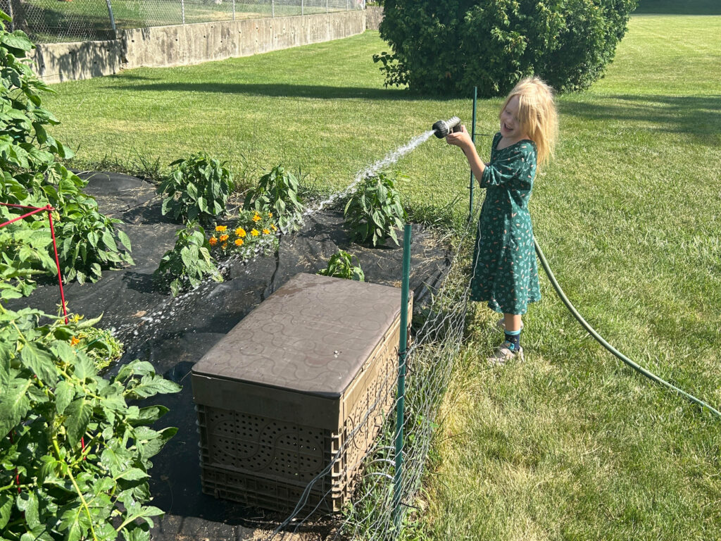 girl watering garden with a hose