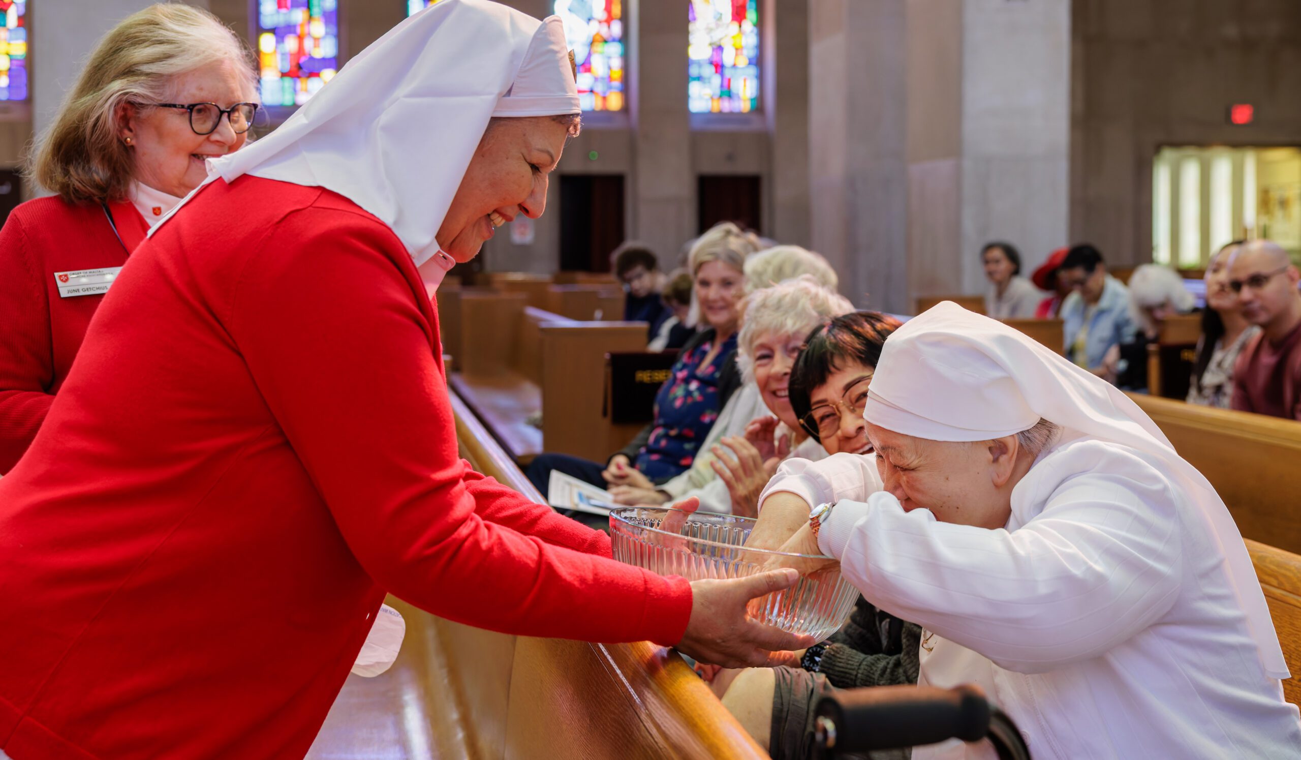 Gina Raymond, a Dame of Malta, offers water for washing from Lourdes, France, during the 12th annual “Lourdes in a Day Pilgrimage of the Sick” at the Cathedral of St. Joseph in Hartford. PHOTO BY AARON JOSEPH