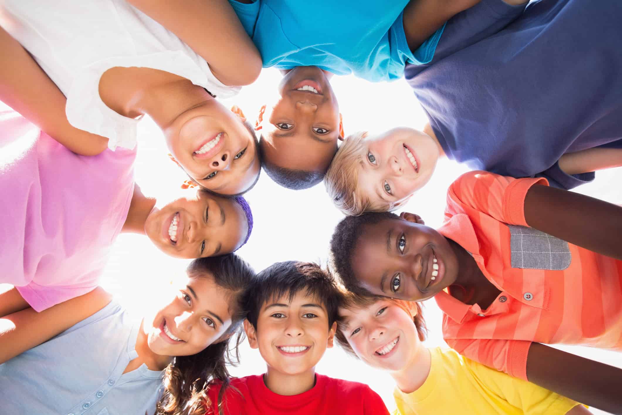 Group of smiling children in a circle staring down