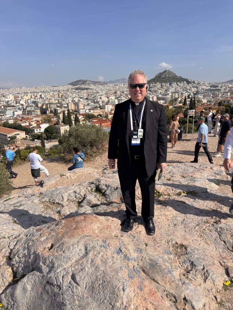 Fr. Wilson standing on the rock of the Areopagus with Athens behind him