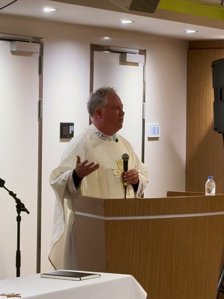 Fr. Wilson preaching with a microphone at the ambo