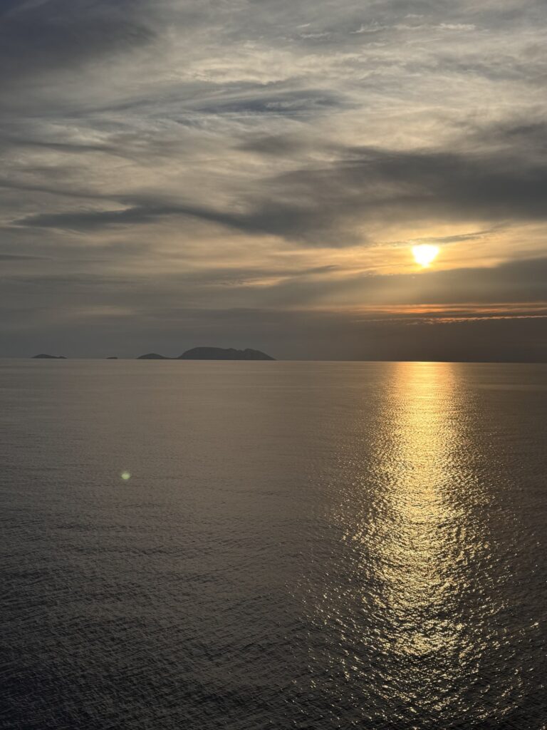 The sun over distant islands, reflected on the water