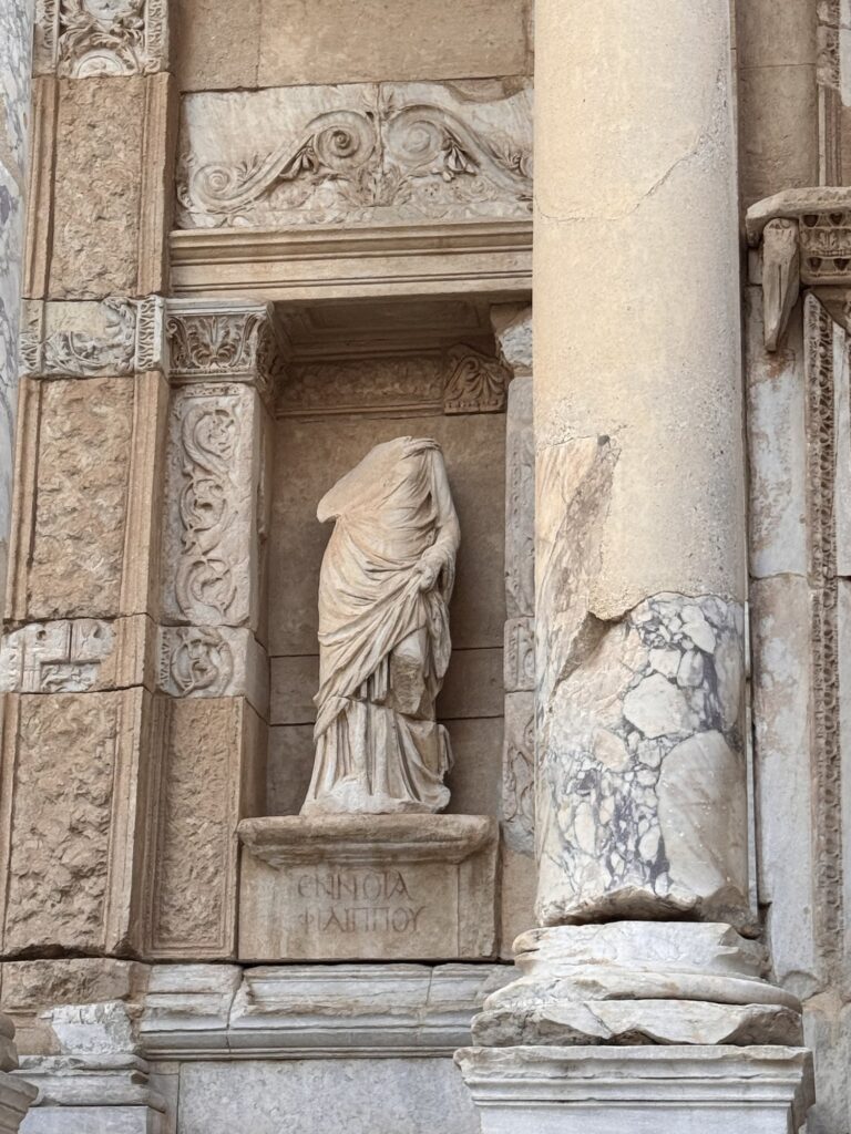 A headless marble statue in a niche on the Library of Celsus