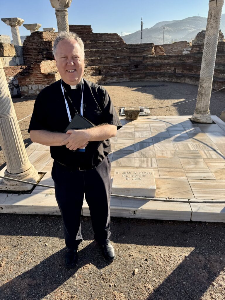 Fr. Jonathan Wilson standing beside the tomb of St. John in the basilica ruins