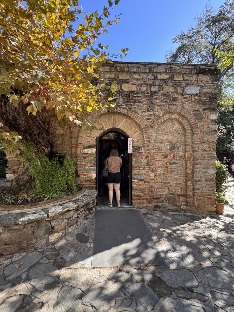 A pilgrim stepping through the arched doorway of the House of Mary