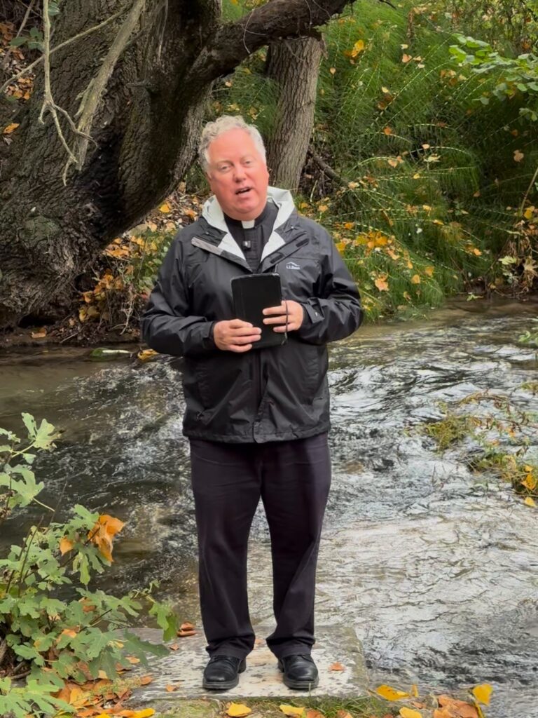Fr. Jonathan Wilson speaking beside the rushing river outside Philippi