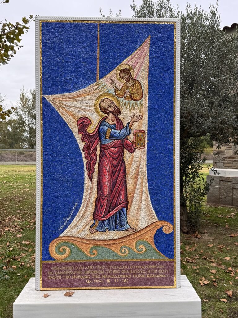 A mosaic of St. Paul at sea beneath a billowing sail, with the text of Acts 16:11-12 in Greek