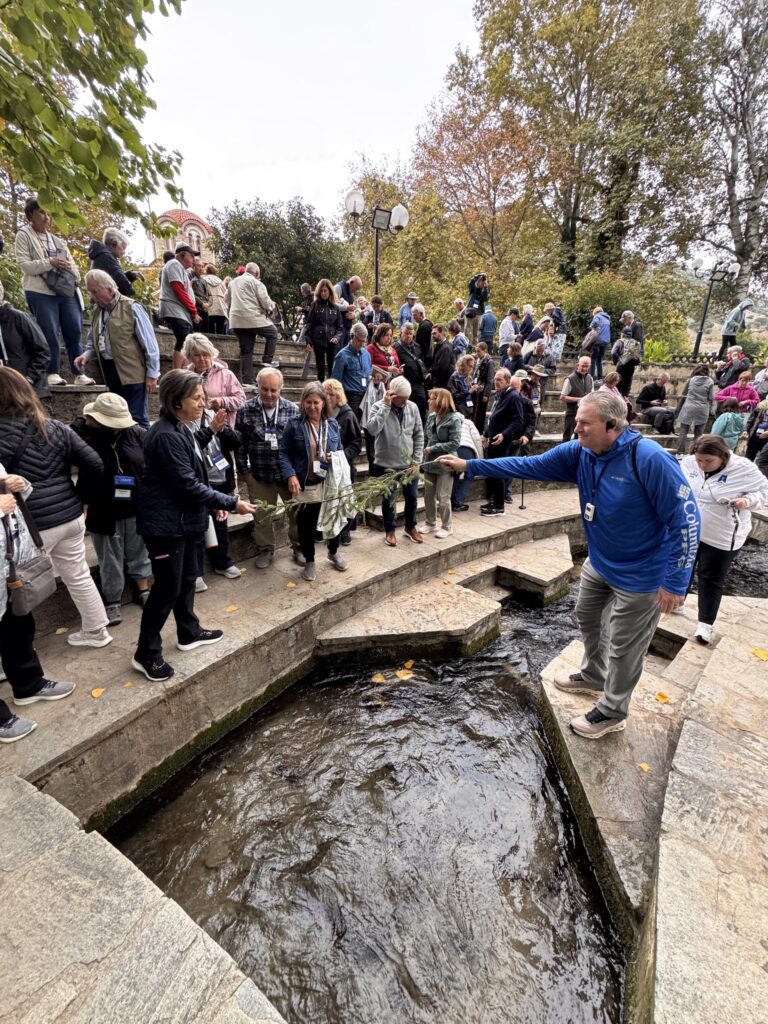 Pilgrims reaching into the water of the stone channel at the baptistery of St. Lydia