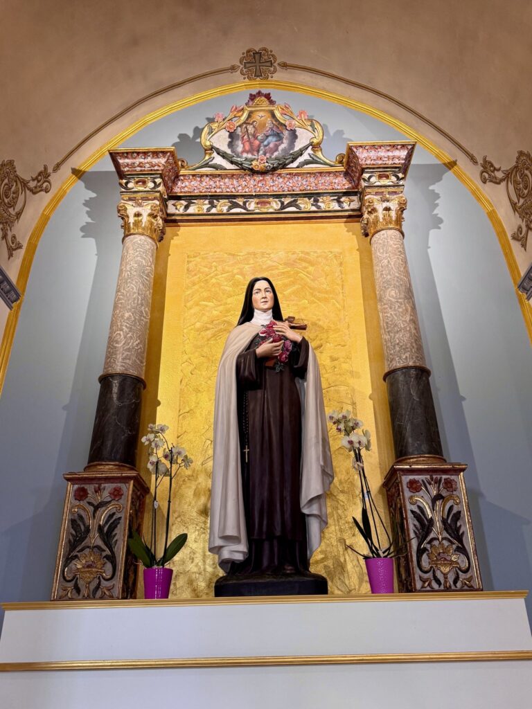 A statue of St. Thérèse of Lisieux in a gilded side altar
