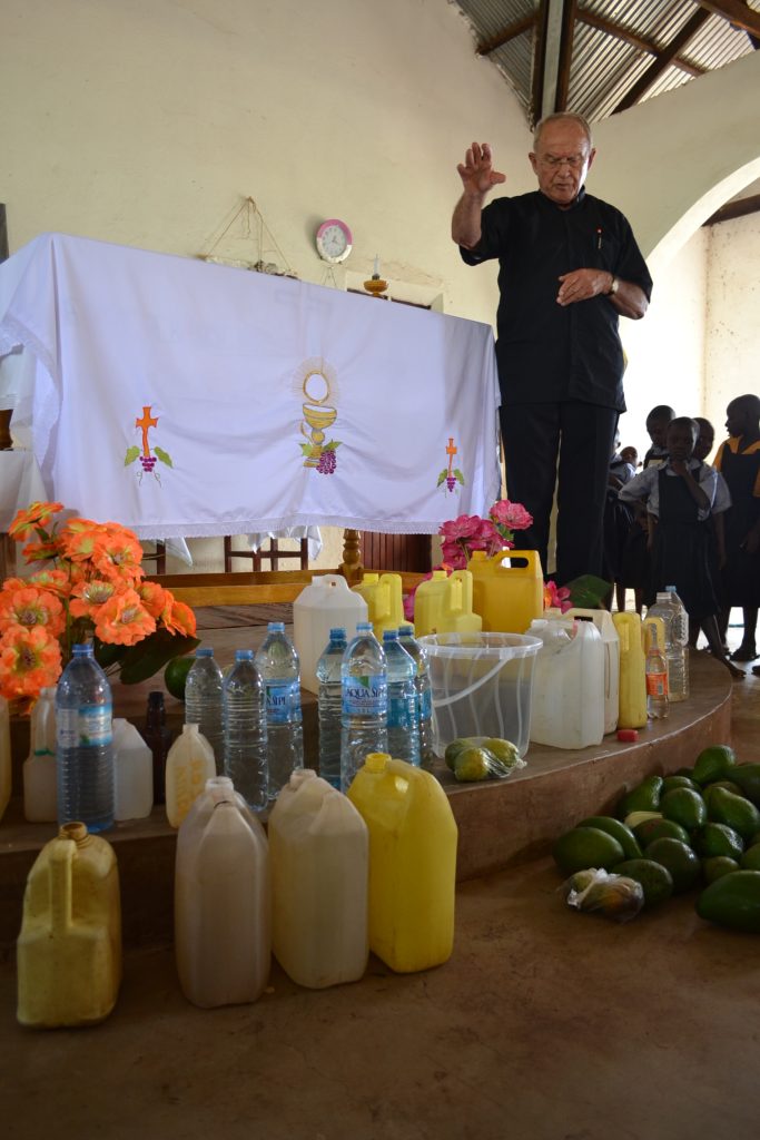 priest blesses water in front of altar