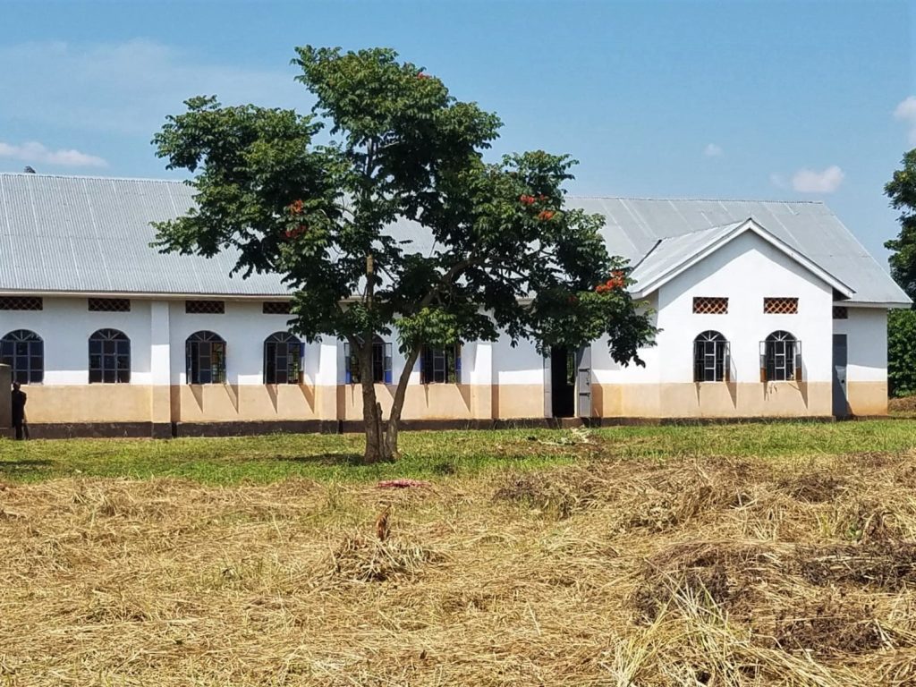 white and tan church with trees in front