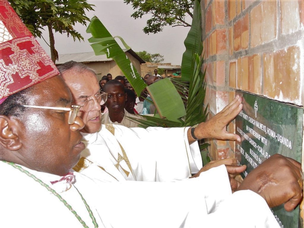 2 men push silver plaque against wall brick wall