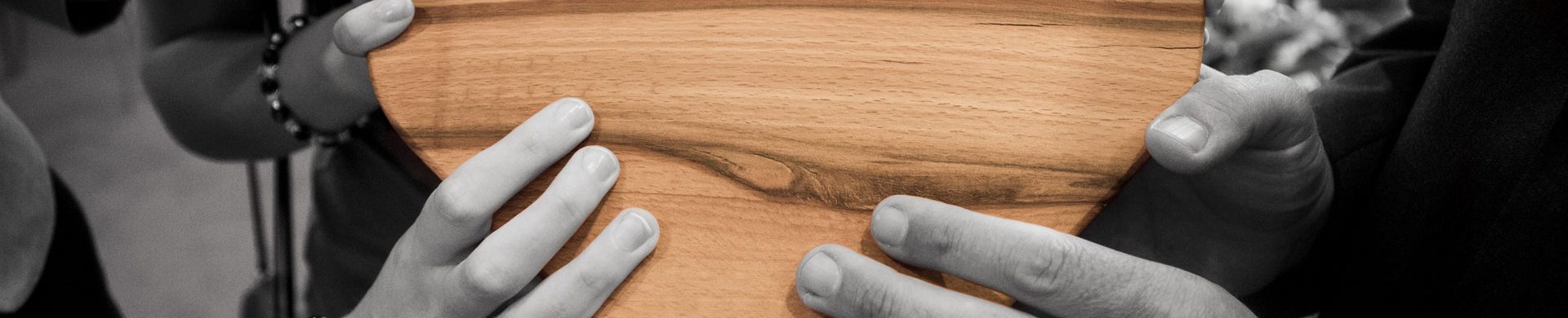 Four set of hands holding a wooden heart