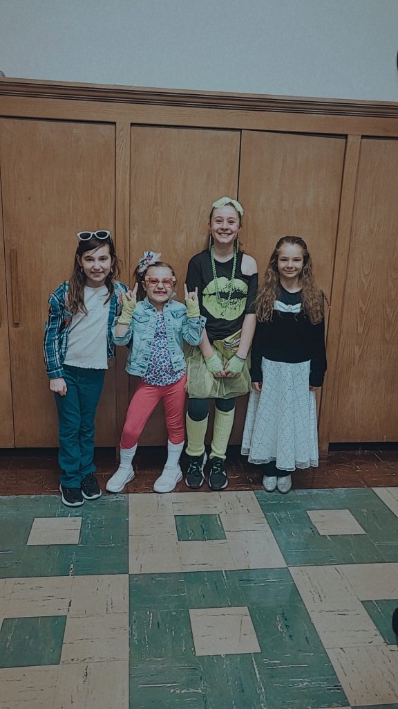 Group of students in the front office of the school dressed in their best 80s attire