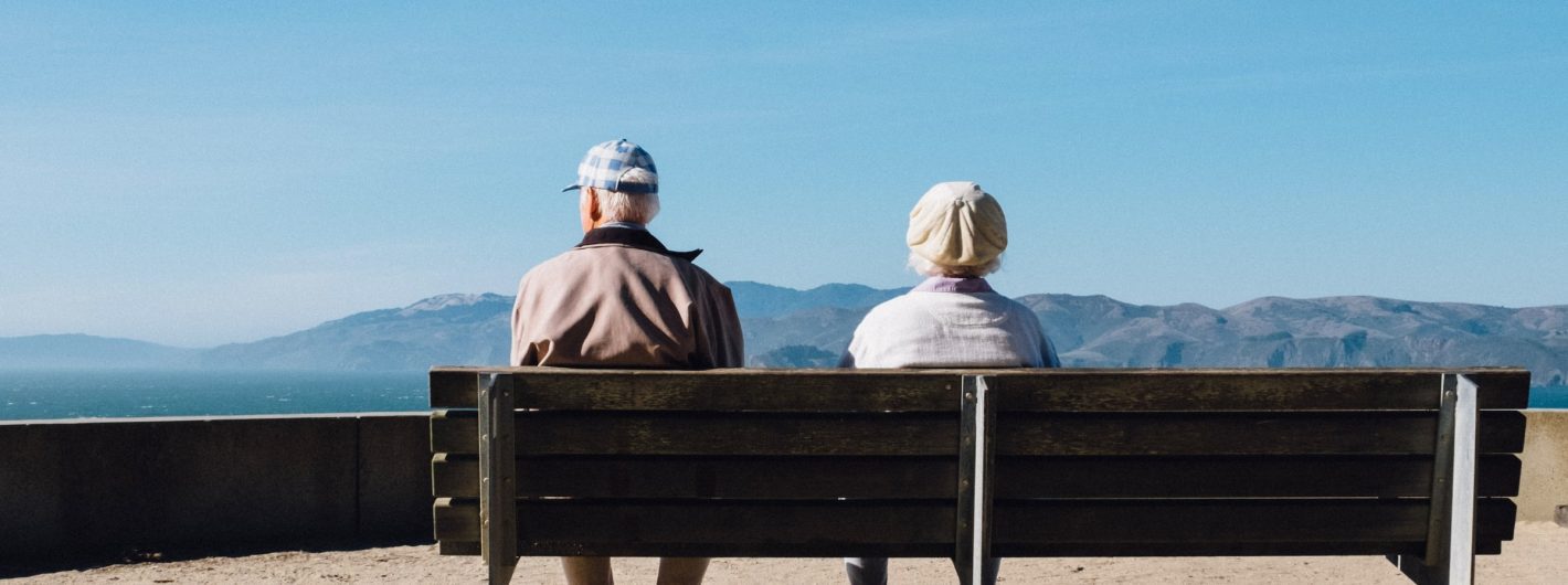 Two Older People on Bench viewing mountains