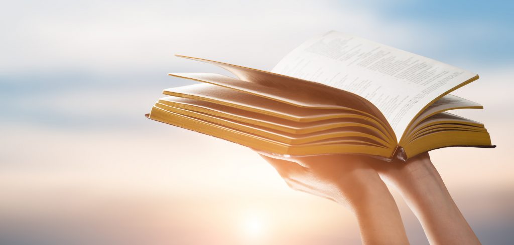 Person holding bible at Sunset
