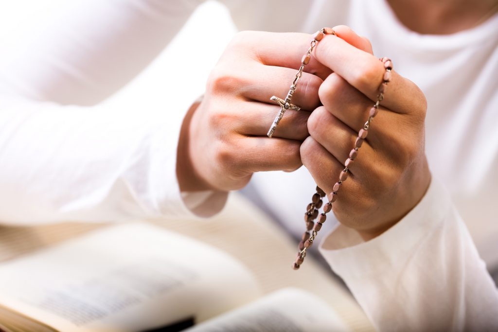Woman praying, holding rosary beads