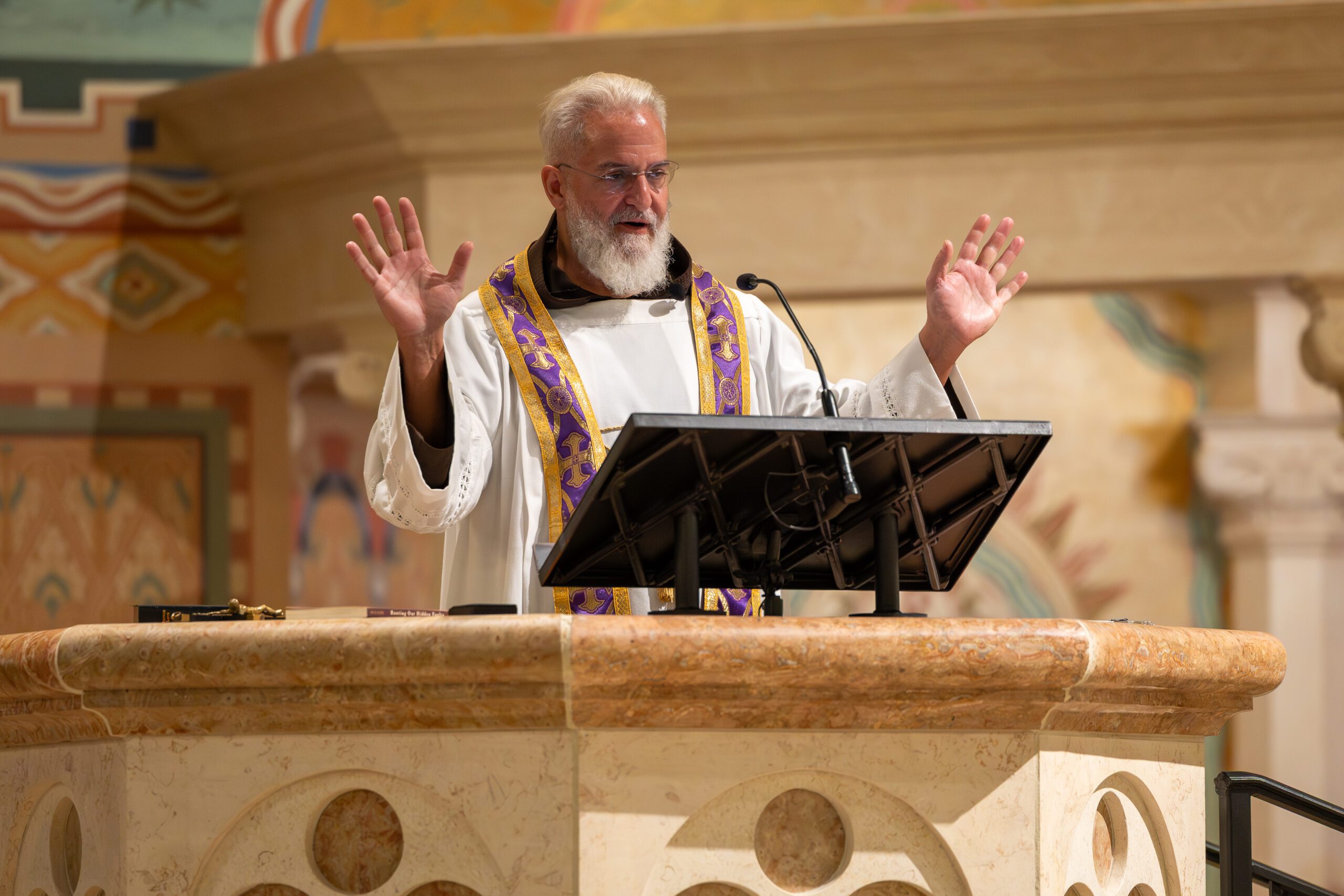 Fr. Joseph Tuscan preaching with arms raised during the Lenten Mission